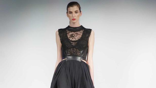 Eine Frau präsentiert ein schwarzes Kleid mit Spitze und einem weiten Rock.