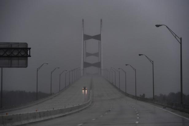 Ein Auto fährt auf einer Brücke im Nebel.