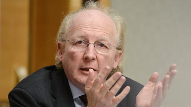 Ein Mann mit Brille gestikuliert mit seinen Händen.