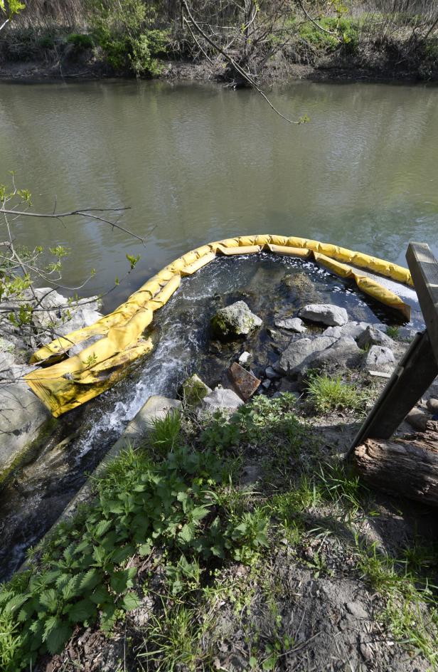 Ein gelber Ölsperre schwimmt in einem Fluss, um die Ausbreitung von Öl zu verhindern.