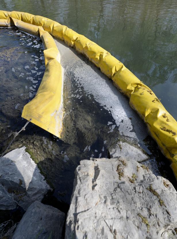 Eine gelbe Ölsperre schwimmt auf einem Fluss, um Verunreinigungen einzudämmen.