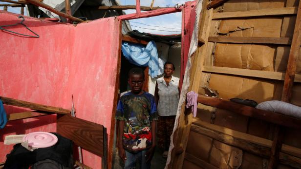 Ein Junge und eine Frau stehen in einem beschädigten Haus.