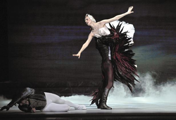 Eine Ballerina in einem schwarzen Tutu steht über einem am Boden liegenden Tänzer.