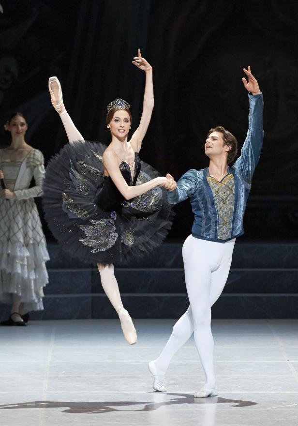 Eine Ballerina in einem schwarzen Tutu und ein Tänzer in einem blauen Kostüm führen eine Ballettnummer auf.