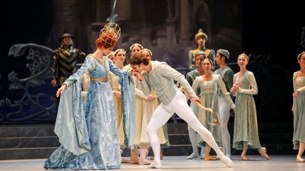 Eine Ballettaufführung mit einer Tänzerin in einem blauen Kleid und einem Tänzer, der ihre Hand küsst.