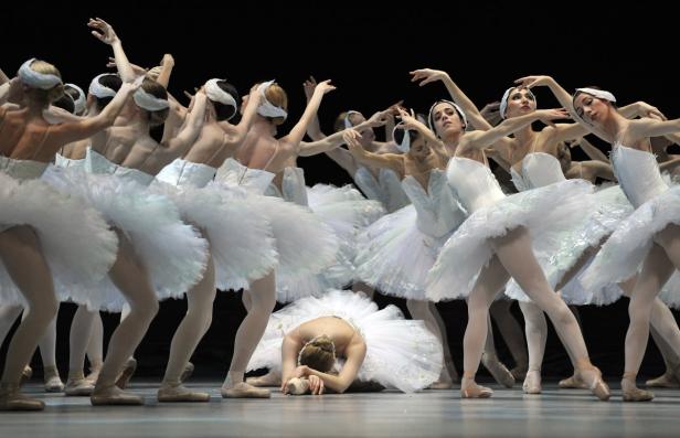 Eine Gruppe von Ballerinen in weißen Tutus tanzt auf einer Bühne, eine liegt am Boden.