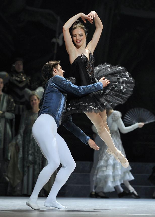 Eine Ballerina in einem schwarzen Tutu wird von einem Tänzer auf der Bühne gehalten.