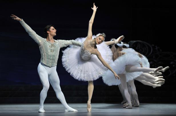 Eine Ballerina und ein Tänzer führen „Schwanensee“ auf einer Bühne auf.