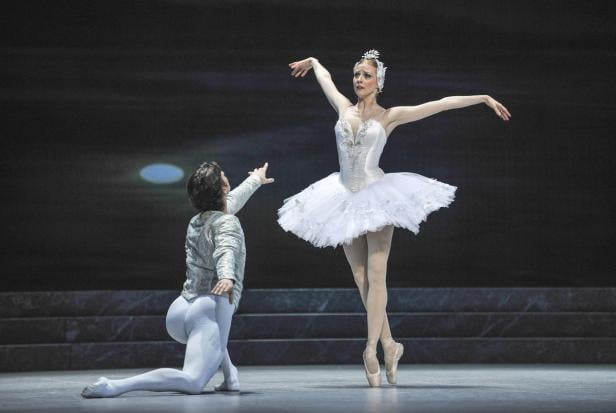 Eine Ballerina im weißen Tutu tanzt mit einem Tänzer auf einer Bühne.