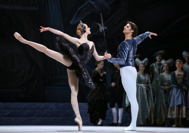 Eine Ballerina im schwarzen Tutu tanzt mit einem männlichen Tänzer auf der Bühne.