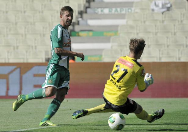 Ein Fußballspieler in Grün läuft auf einen Torwart zu, der versucht, den Ball abzuwehren.
