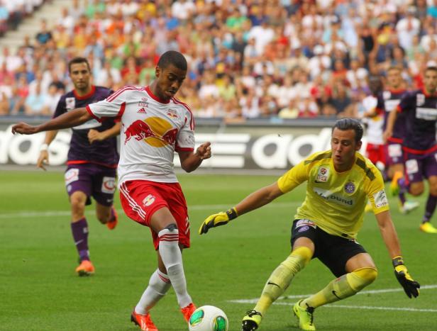 Ein Fußballspieler von Red Bull Salzburg dribbelt den Ball, während ein gegnerischer Torwart sich nähert.
