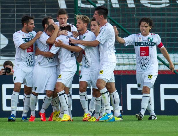 Eine Gruppe Fußballspieler des FC Wacker Innsbruck feiert gemeinsam auf dem Spielfeld.