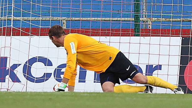 Ein Torwart in gelbem Trikot kniet vor dem Tor und hält einen Ball.