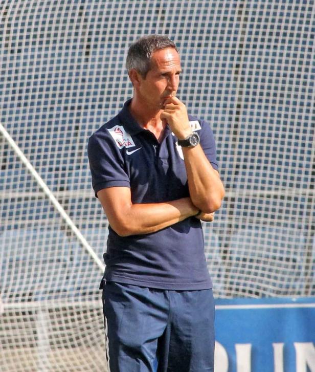 Ein Mann in Sportkleidung steht nachdenklich vor einem Netz.