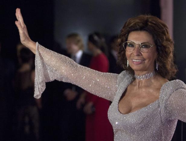 Sophia Loren in einem glitzernden Kleid mit ausgestrecktem Arm.