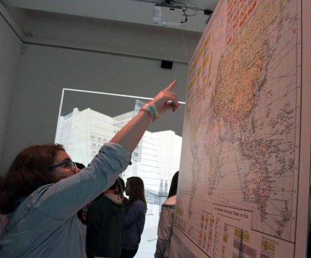 Eine Frau zeigt auf einer Weltkarte auf einen bestimmten Punkt.