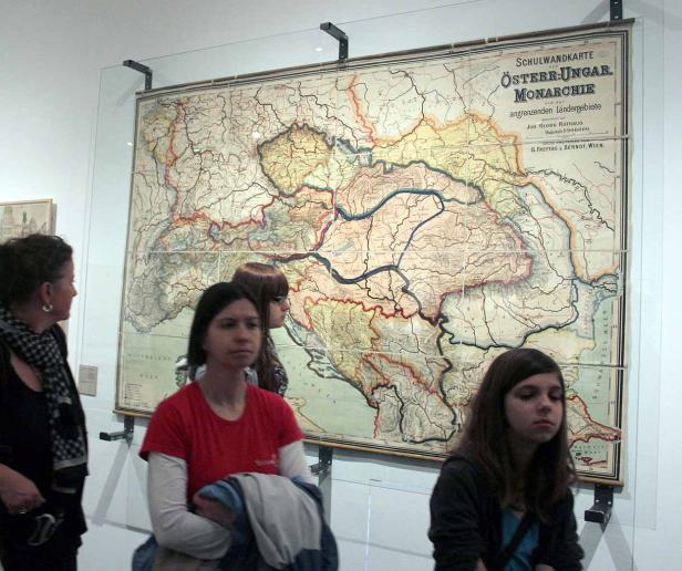 Besucher betrachten eine alte Schulwandkarte der Österreichisch-Ungarischen Monarchie.