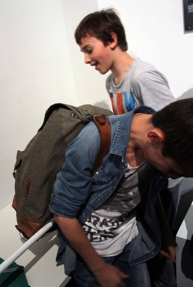 Zwei Jugendliche gehen eine Treppe hinauf, einer mit einem großen Rucksack.