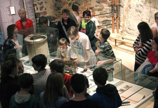 Eine Gruppe von Menschen betrachtet Ausstellungsstücke in einem Museum.