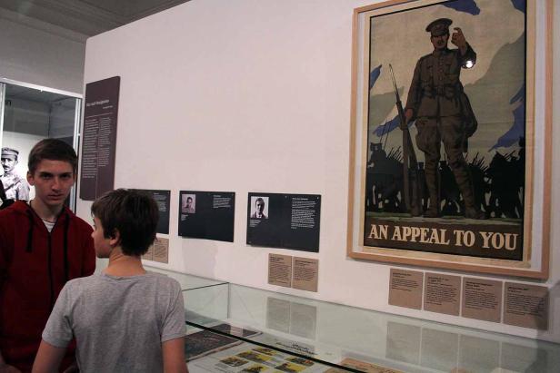 Zwei Jungen betrachten ein Kriegsposter in einem Museum.