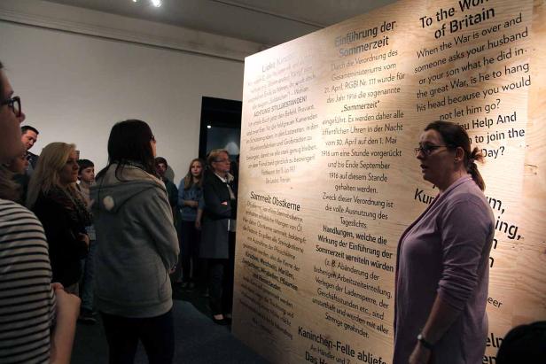 Eine Gruppe von Menschen betrachtet eine Ausstellungstafel mit Texten über den Ersten Weltkrieg.