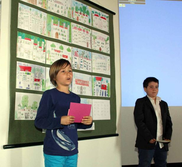 Zwei Jungen präsentieren Kinderzeichnungen von Häusern.