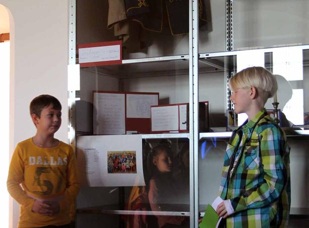 Zwei Jungen betrachten eine Vitrine mit Ausstellungsstücken.