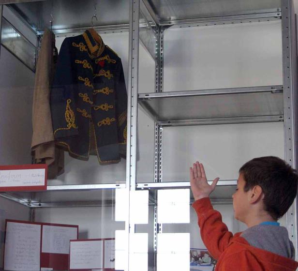 Ein Junge betrachtet eine historische Uniform in einer Vitrine.