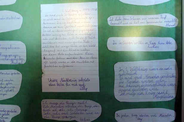 Auf dem Bild sind handgeschriebene Zitate und Texte zum Thema Krieg auf Papierstücken zu sehen.