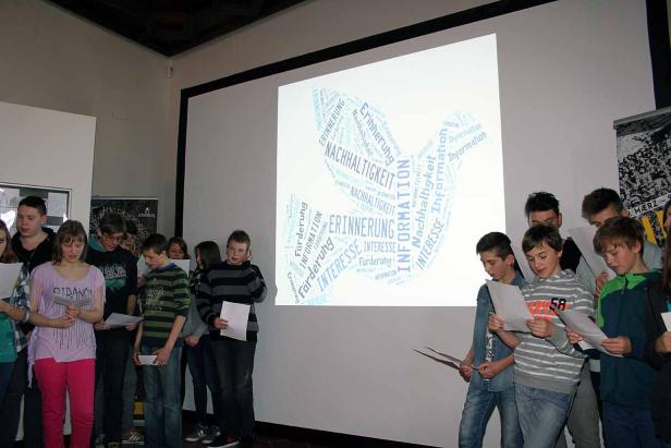 Eine Gruppe von Schülern steht vor einer Leinwand mit einer Wortwolke zum Thema Nachhaltigkeit.