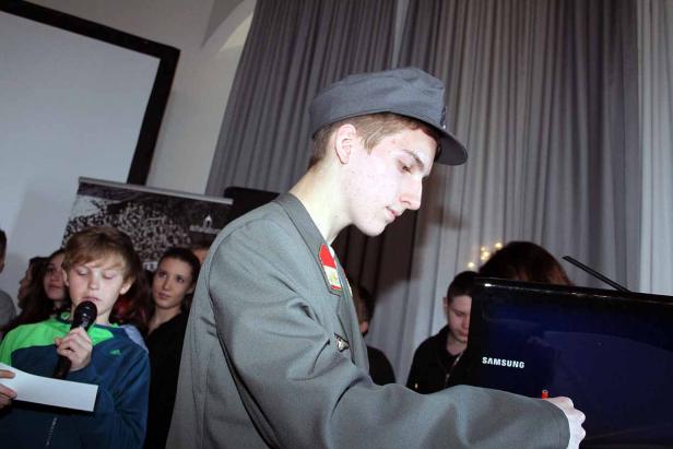 Ein junger Mann in Uniform steht an einem Laptop und schreibt.