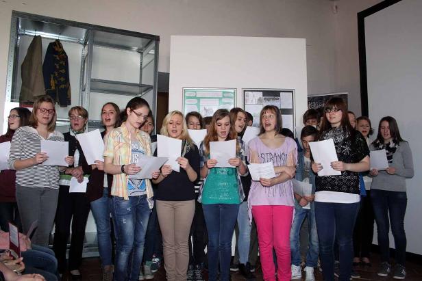 Ein Jugendchor singt mit Notenblättern in der Hand.