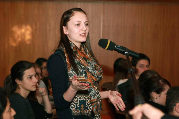 Eine junge Frau spricht während einer Präsentation in ein Mikrofon.