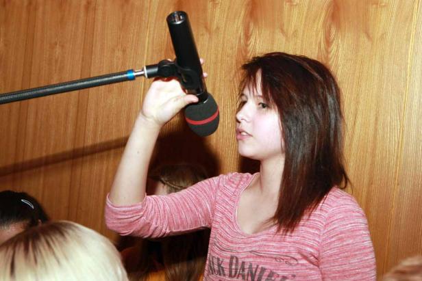 Eine junge Frau hält ein Mikrofon in der Hand.