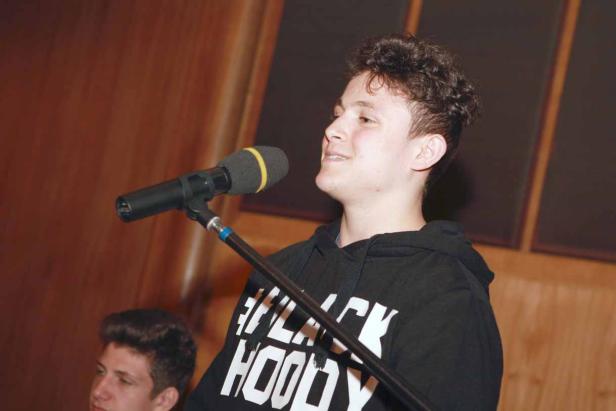 Ein junger Mann singt in ein Mikrofon.