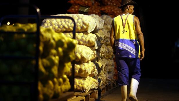 Ein Mann mit Cowboyhut steht vor Säcken voller Zwiebeln.