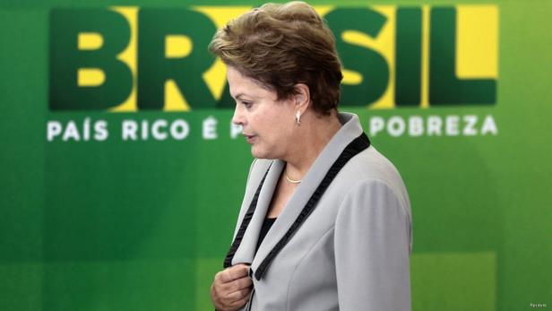 Dilma Rousseff steht vor einem grünen Hintergrund mit der Aufschrift „Brasil“.
