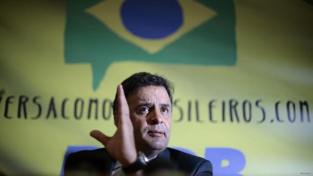 Ein Mann gestikuliert vor einem Hintergrund mit der brasilianischen Flagge.