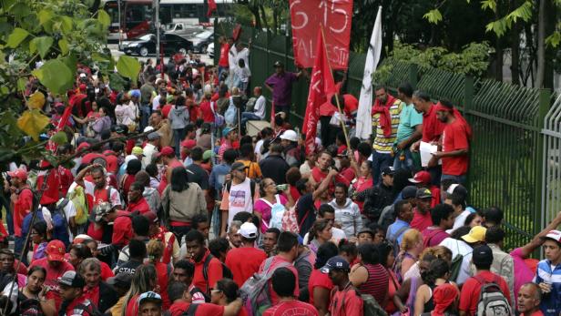 Eine große Menschenmenge demonstriert mit roten Fahnen und Transparenten auf der Straße.