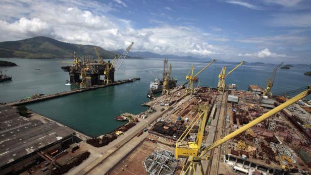 Blick auf eine Werft mit Kränen und einer Ölplattform im Wasser.