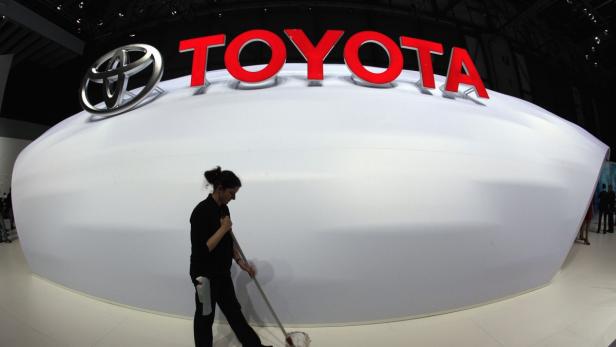 Eine Frau wischt den Boden vor einem großen Toyota-Logo.