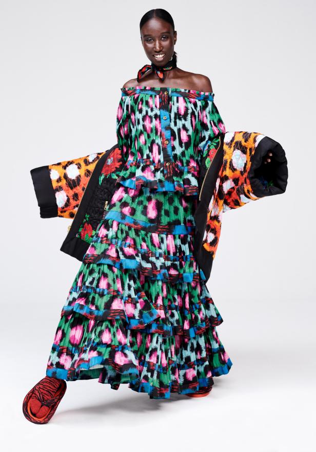 Eine Frau in einem farbenfrohen, mehrlagigen Kleid mit Leopardenmuster und passender Jacke.