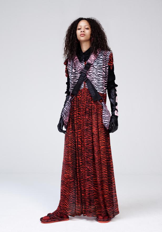 Eine Frau in einem langen Kleid mit Tigerprint und passenden Accessoires posiert.