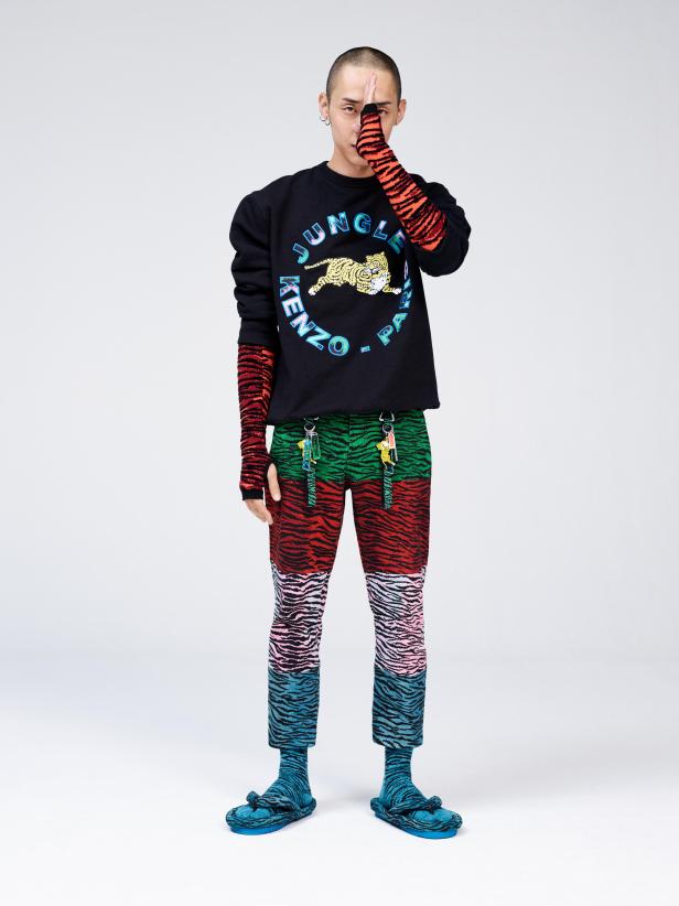 Ein Mann in einem Kenzo-Outfit mit Tiger-Motiven posiert vor einem weißen Hintergrund.