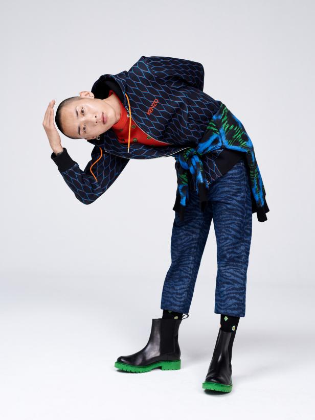 Ein Mann in einem Kenzo-Outfit posiert vor einem weißen Hintergrund.