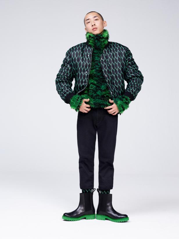 Ein Mann in einer schwarzen Hose und einer Jacke mit grünem Muster und grünen Akzenten.