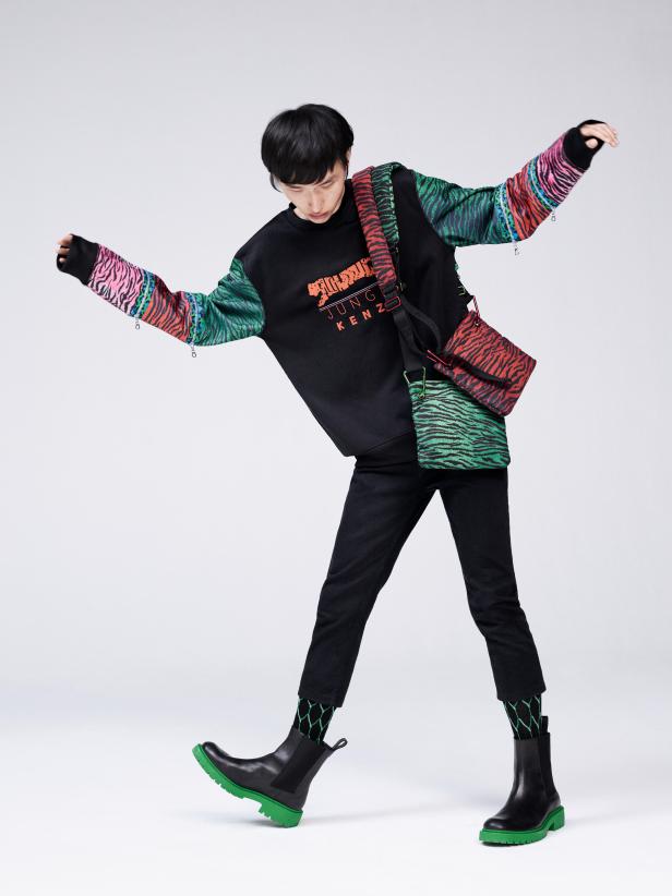 Ein Mann in einem farbenfrohen Outfit der Marke Jung Kenzo posiert vor einem weißen Hintergrund.