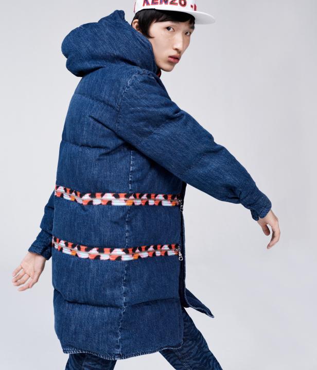 Ein asiatisches Model trägt eine Jeansjacke mit Kapuze und eine Kappe mit der Aufschrift „Kenzo“.
