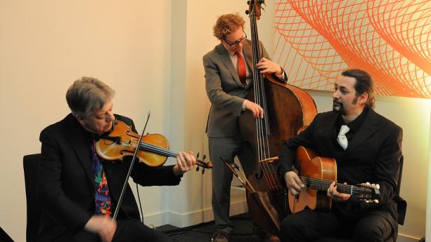 Ein Trio spielt auf Geige, Kontrabass und Gitarre.